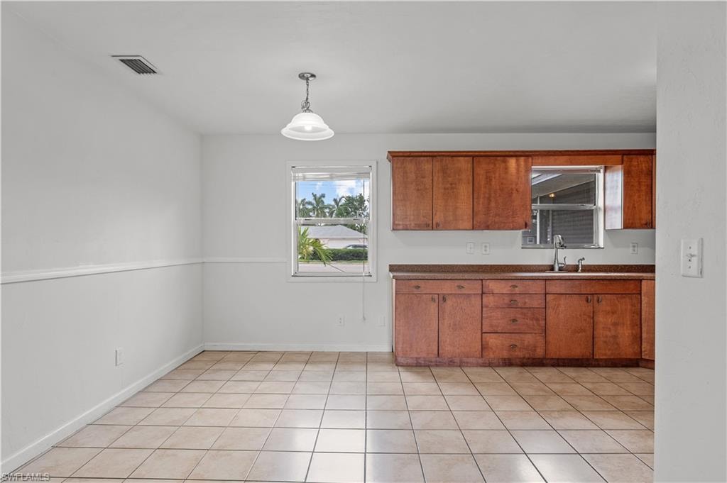 Kitchen with decorative light fixtures, sink, and light tile floors