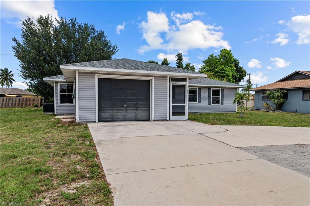 Ranch-style home with a front yard, large circle driveway and a garage