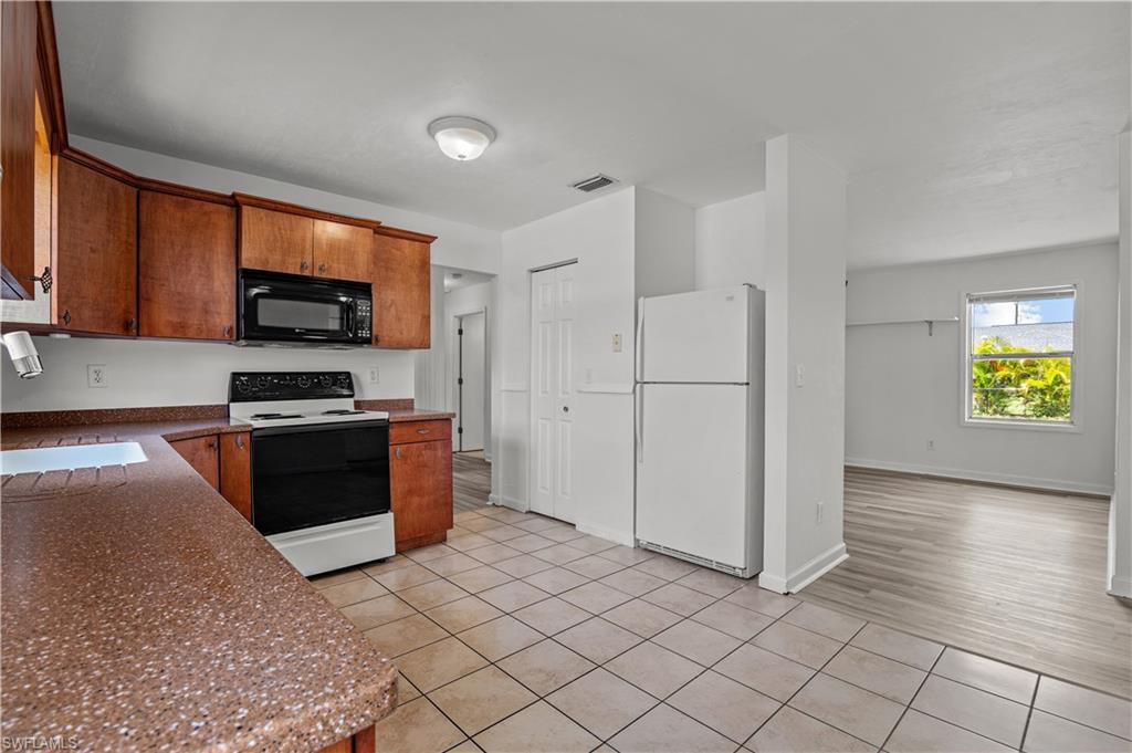 Kitchen with sink, white appliances, and light tile floors