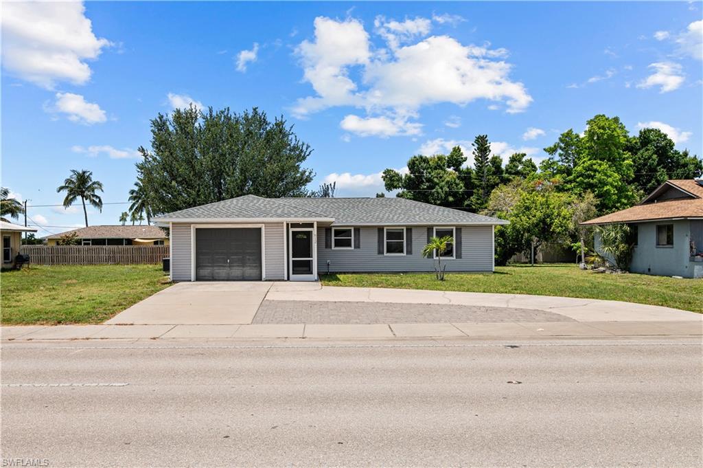 Single story home with a garage, large driveway and a front lawn