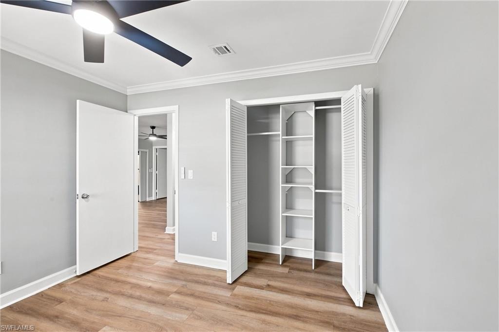 Second  bedroom featuring built-in closet shelving and hanging system, wood-finish flooring, and ceiling fan