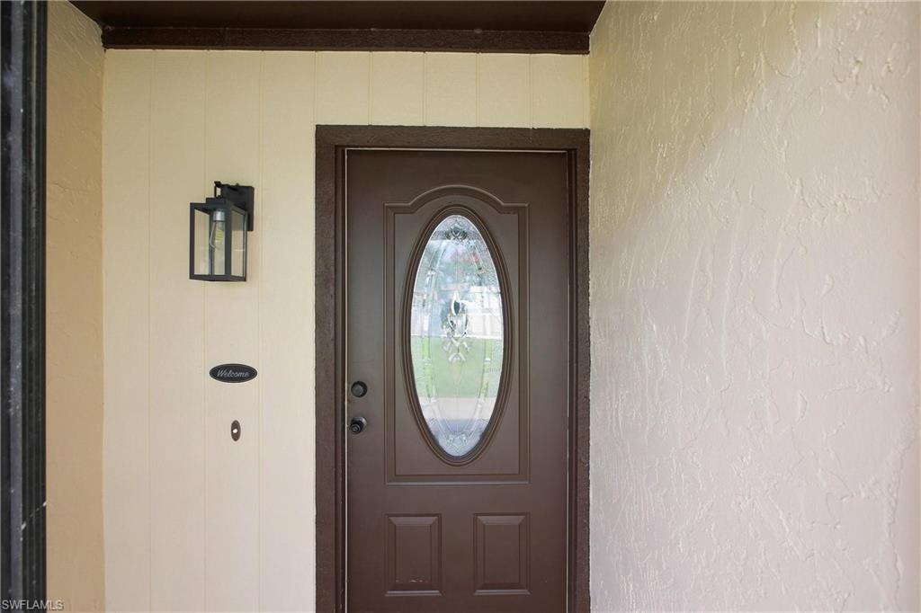 A covered front entryway welcomes guests with a decorative oval glass insert door and a modern exterior light fixture.