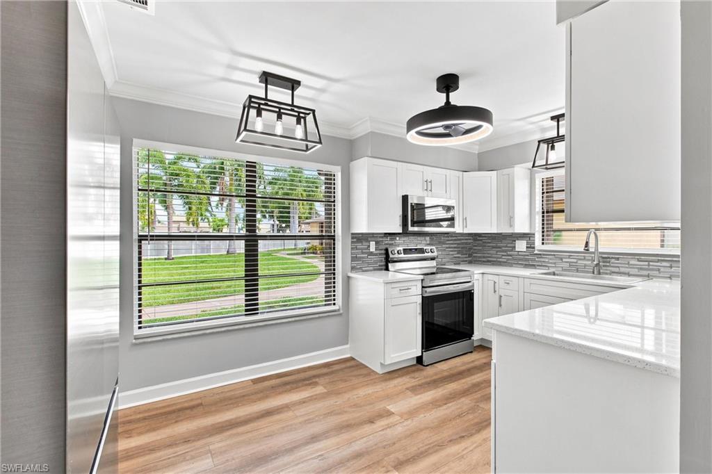Bright eat-in kitchen area features a large window framing scenic outdoor views, stainless steel appliances, and updated modern lighting.