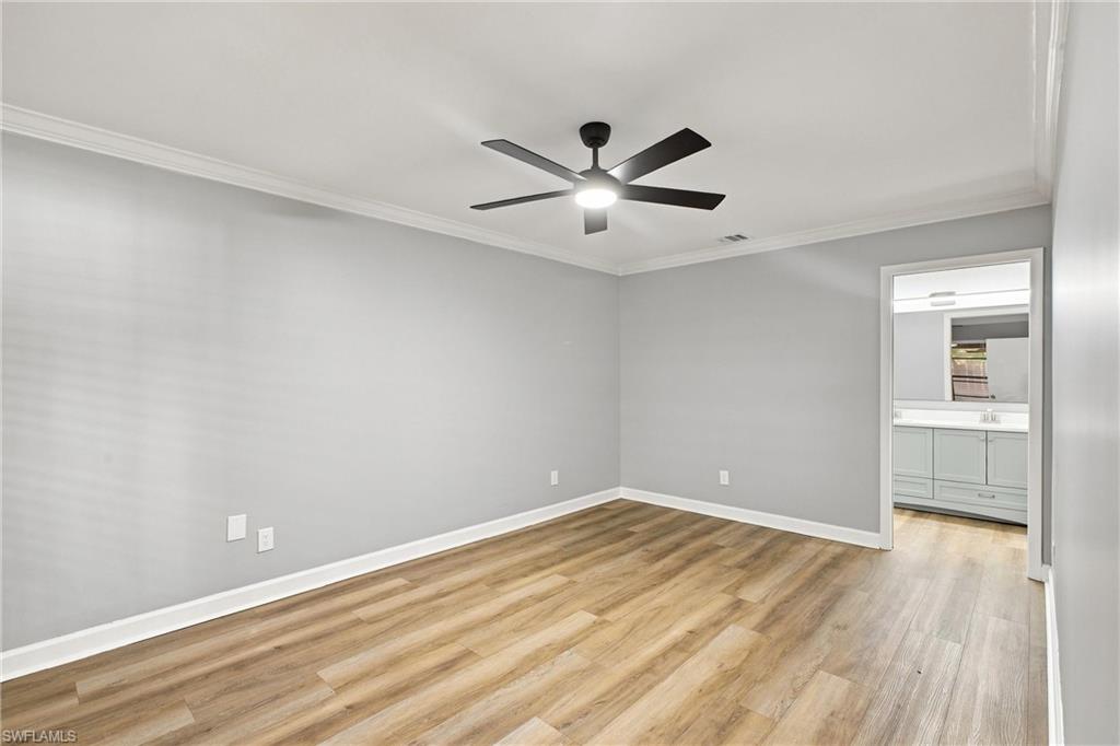 Spacious primary bedroom features private en-suite bathroom access, clean crown molding, and a modern ceiling fan.