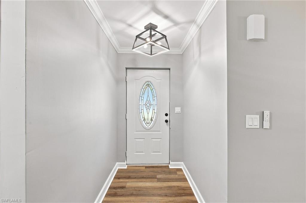 A private interior foyer Welcomes you with fresh neutral paint, detailed crown molding, and an eye-catching modern chandelier.