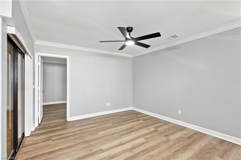 Alternate view of the expansive, open living space highlighting the neutral paint palette, crisp crown molding, and continuous luxury vinyl flooring.