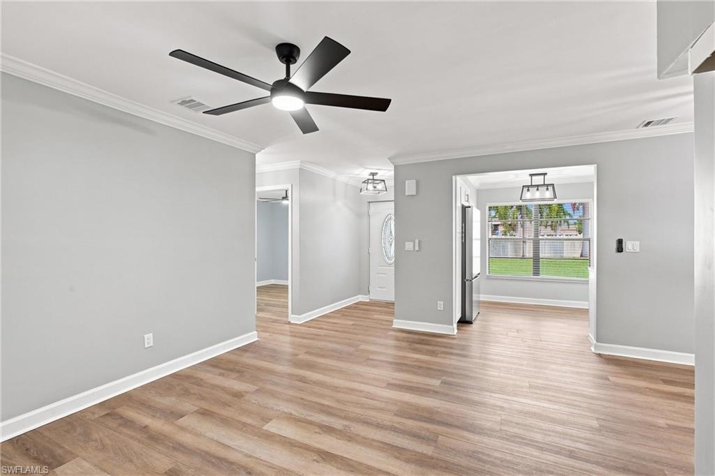 Bright, open-concept living area featuring modern wood-look flooring, crown molding, and a sleek contemporary ceiling fan.
