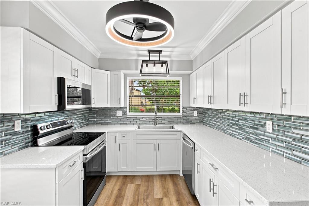 Chef's delight! Beautifully updated kitchen boasts crisp white shaker cabinets, gleaming quartz countertops, and a vibrant glass tile backsplash.