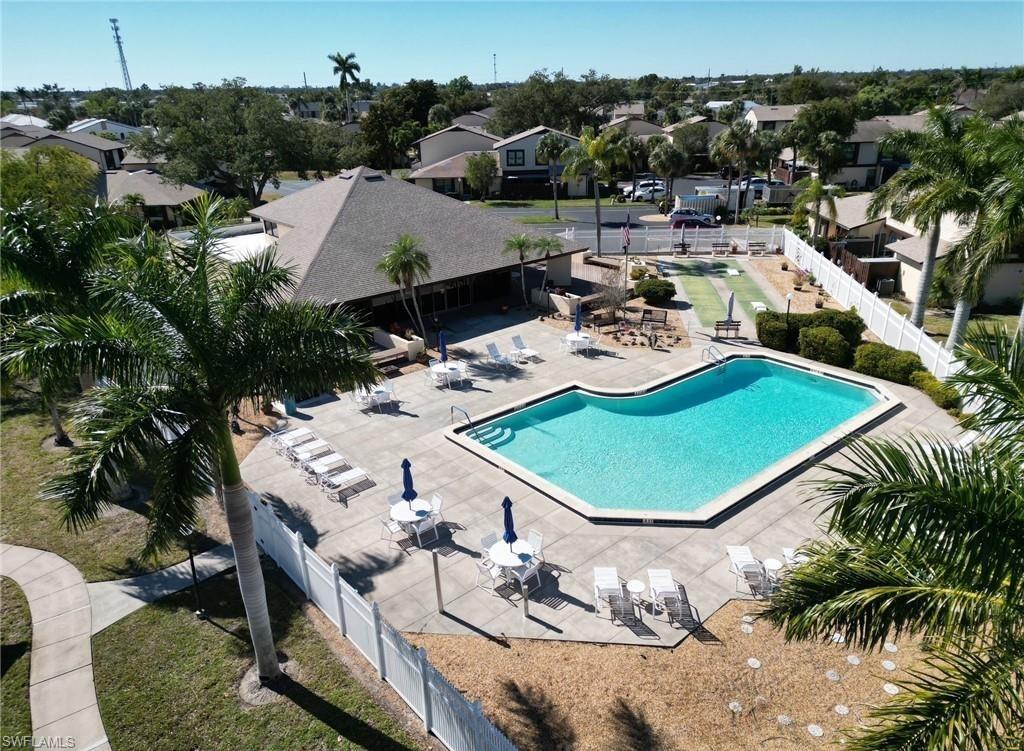 Community swimming pool with a surrounding paved deck, shaded outdoor seating, and a large clubhouse with a pyramid-style roof