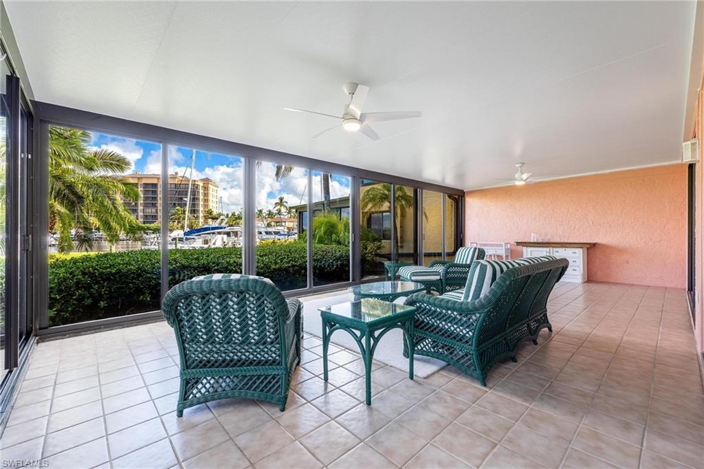 Spacious covered lanai featuring tiled flooring, ceiling fan, and expansive sliding glass doors framing lush landscaping and city vistas