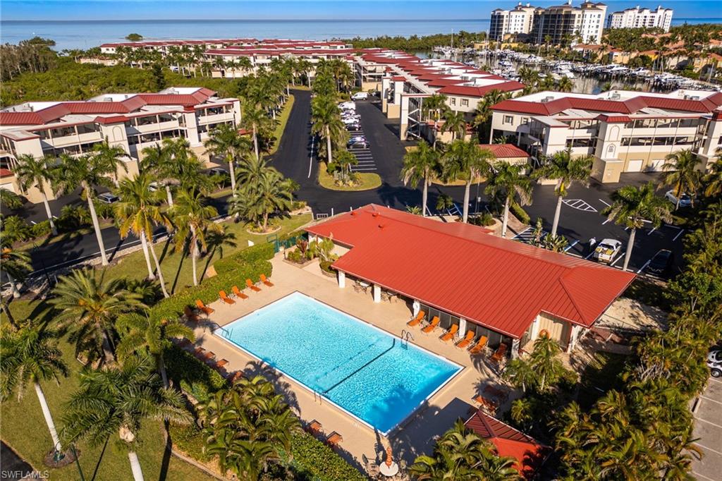 Community pool area featuring a rectangular swimming pool, surrounding lounge seating, and a covered patio structure with a red roof