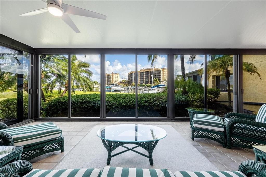 Enclosed sunroom featuring full-height sliding glass panels, tile flooring, and a ceiling fan