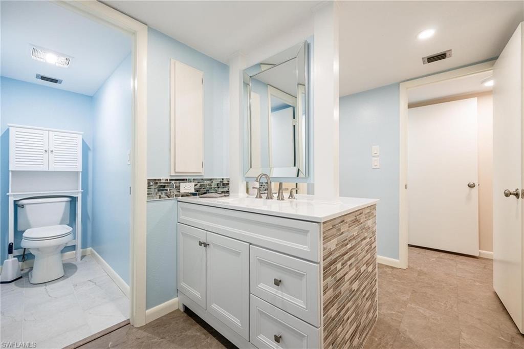 Bathroom vanity featuring a vessel sink, single-handle faucet, and mosaic tile backsplash