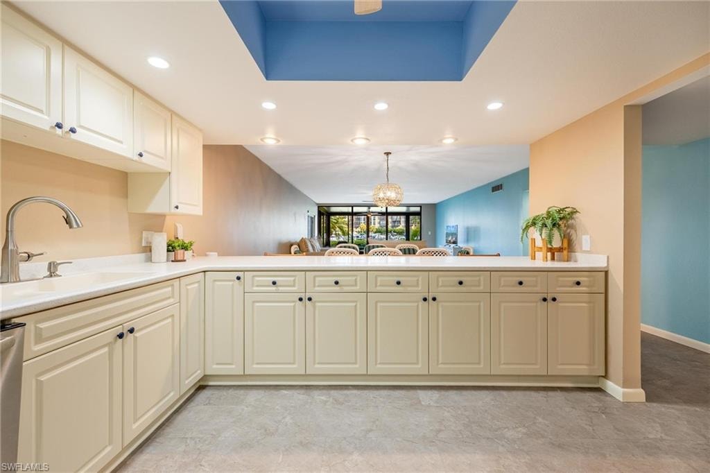 Kitchen featuring cream-colored cabinetry, white countertops, stainless steel sink with gooseneck faucet, recessed lighting, and tile flooring