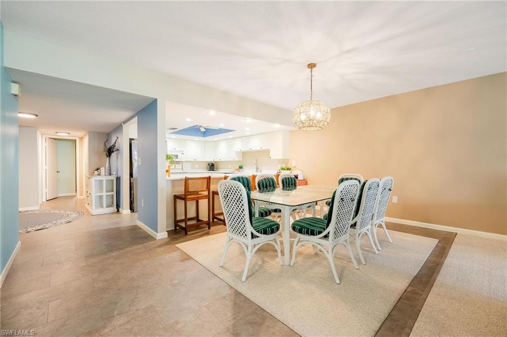 Dining area featuring a contemporary chandelier, neutral wall tones, and an open concept layout