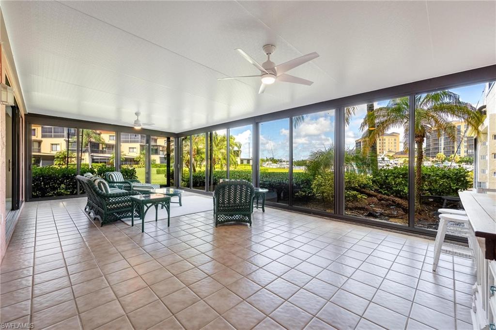 Screened lanai featuring tile flooring, ceiling fans, and a full wall of floor-to-ceiling windows
