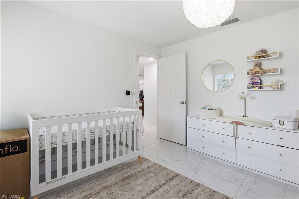 White walls, white paneled door, and a white dresser with clear knobs
