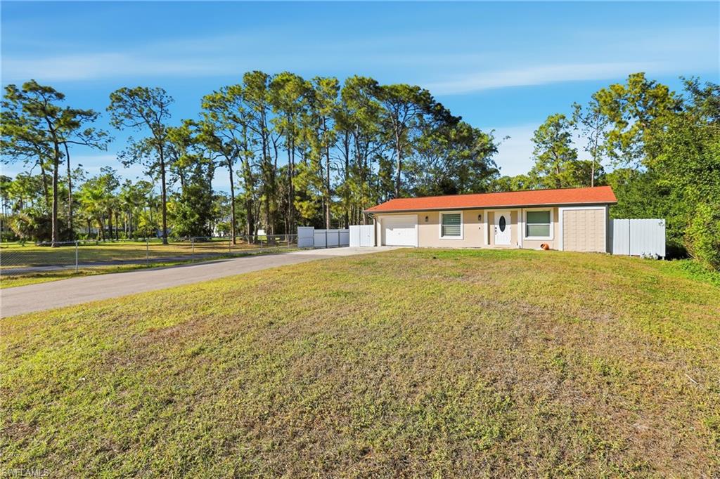 Single-story residence featuring an attached two-car garage, an orange tile roof, and a privacy fence