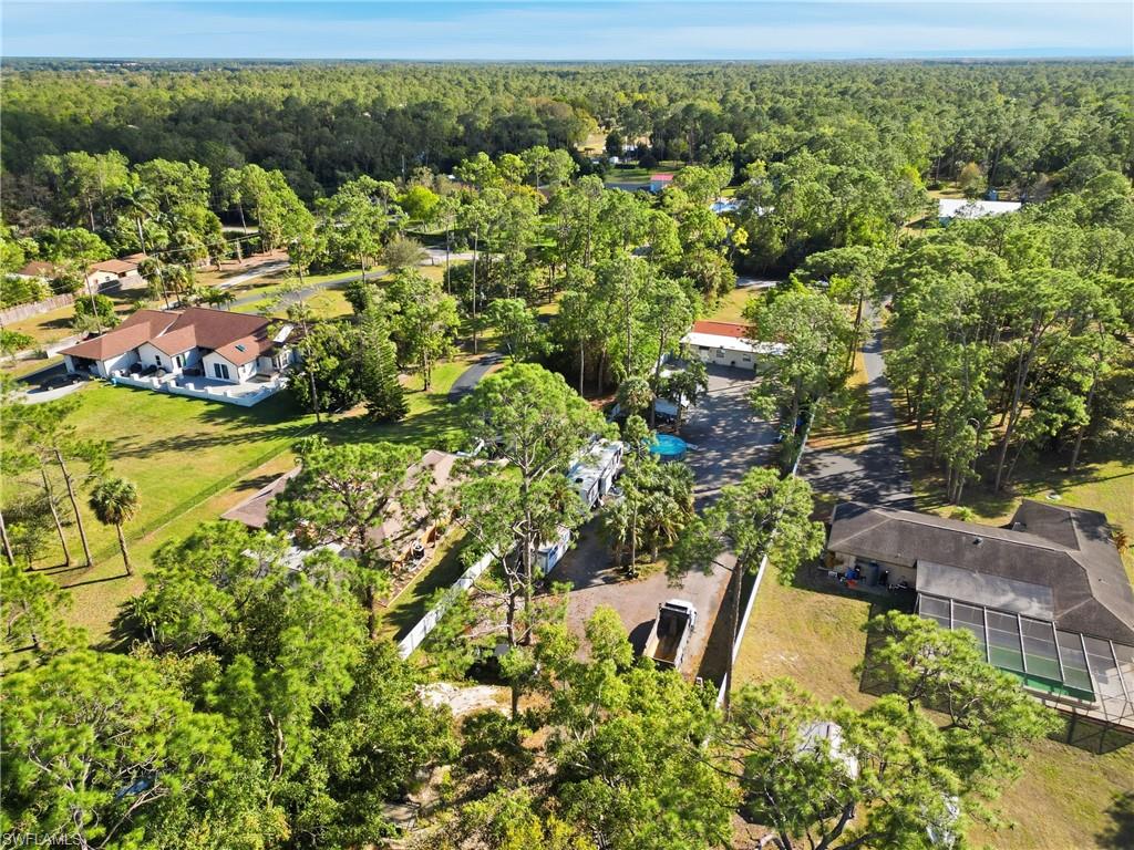 Sprawling property featuring expansive green spaces, mature trees, a swimming pool, and multiple structures