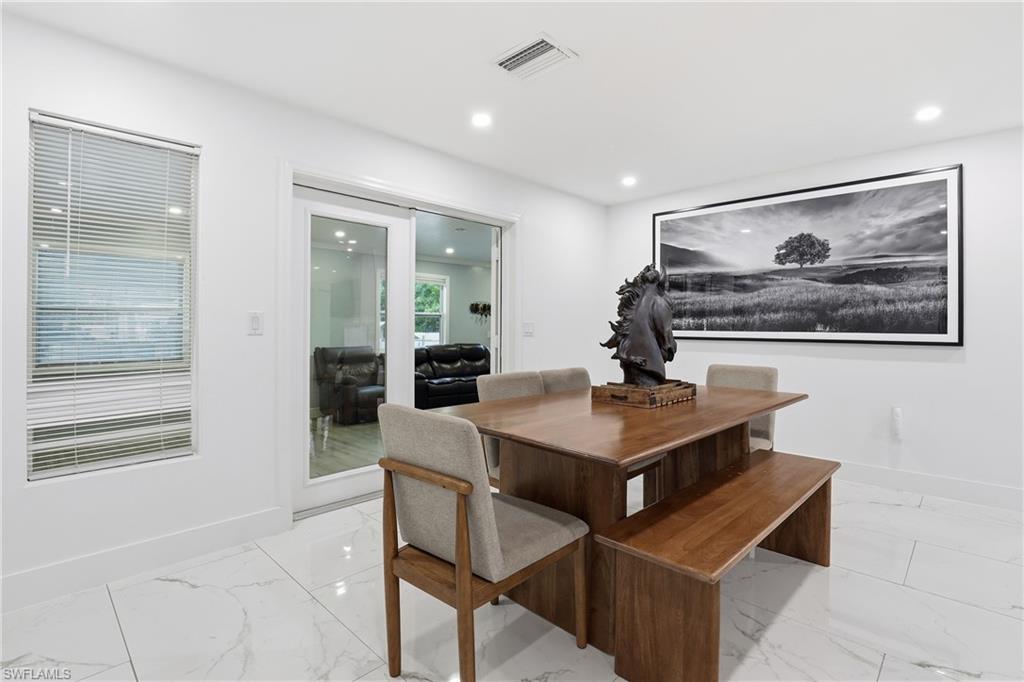 Recessed lighting illuminates the space, featuring white walls, large format tile flooring, and a sliding glass door