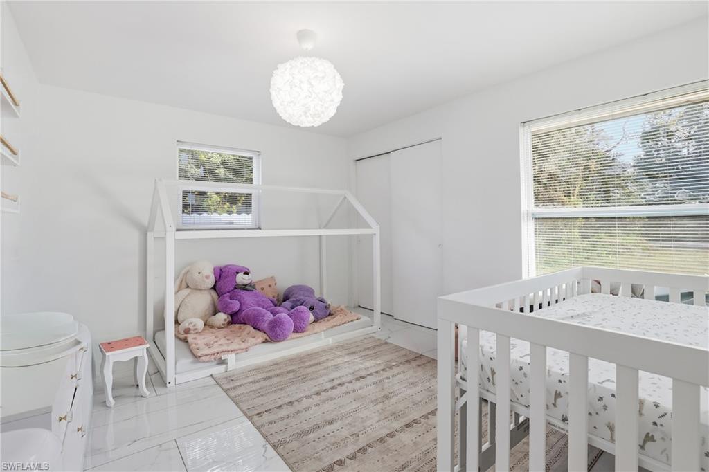 White walls, white tile flooring, and two windows with blinds