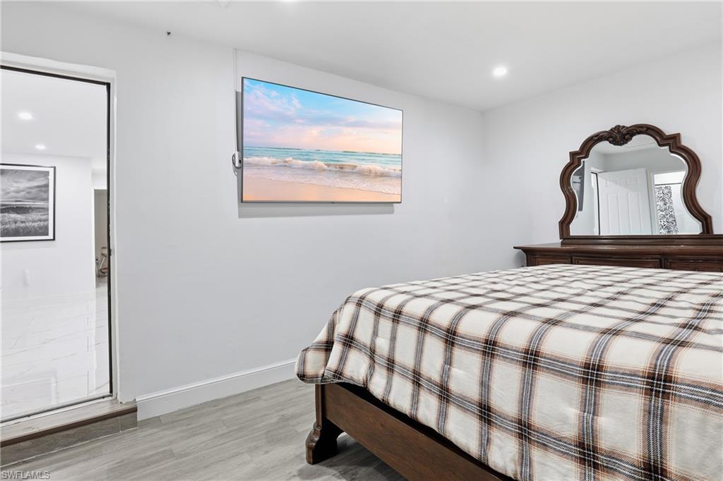 Light gray wood-finish flooring, recessed ceiling lighting, and a modern wall-mounted television