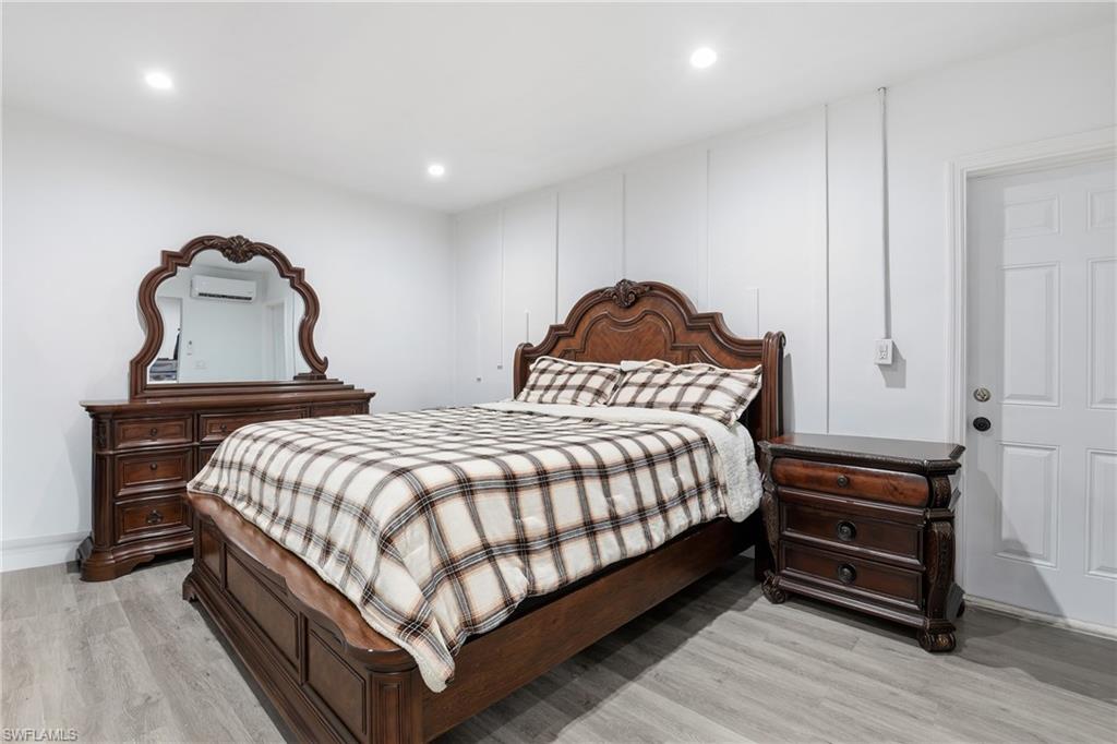 Recessed lighting, wood-finish flooring, white paneling, and a solid white door