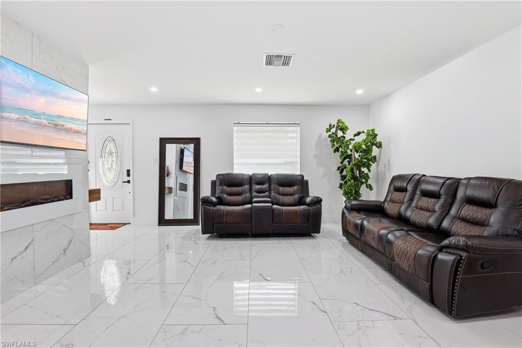 Polished tile flooring, recessed lighting, white walls, and a built-in fireplace feature