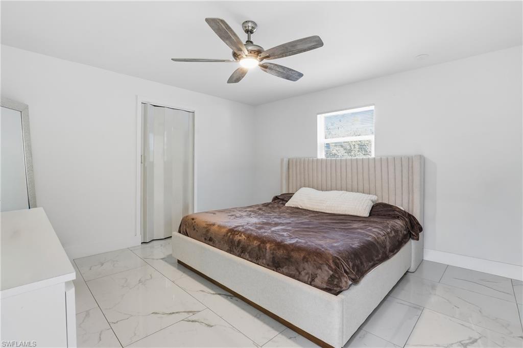 White walls with a window, tile flooring, and a ceiling fan