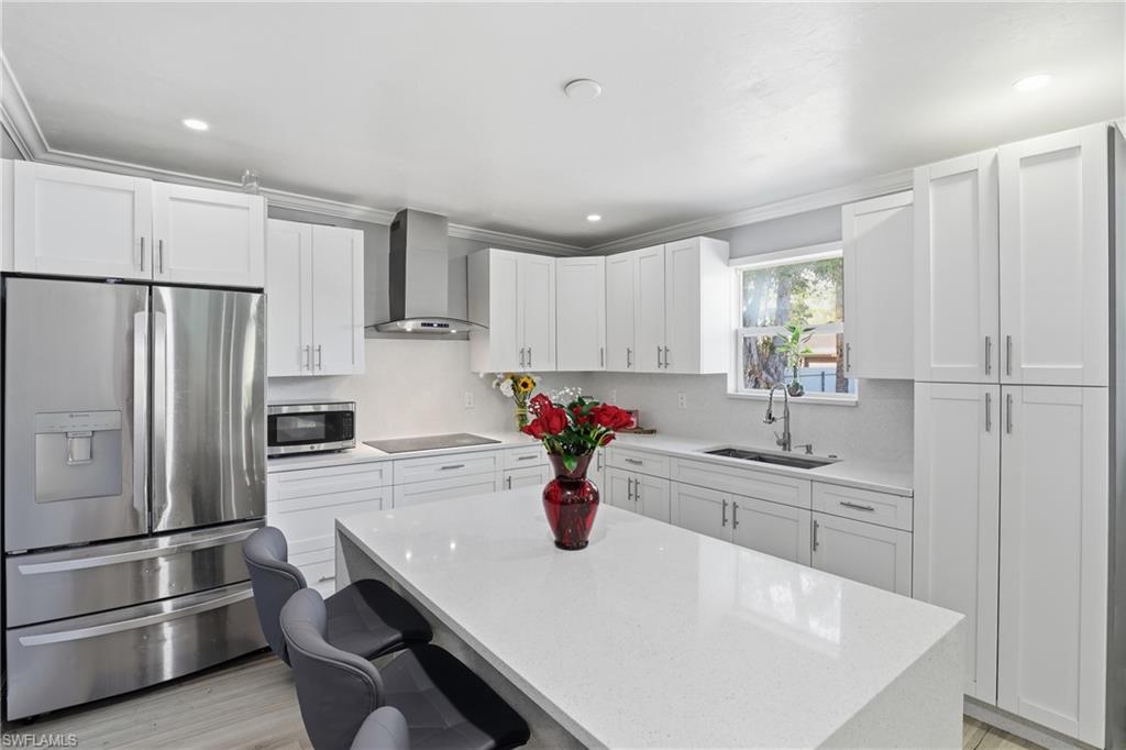 Modern kitchen featuring white shaker cabinetry, stainless steel appliances, a center island with a solid surface countertop, and recessed lighting