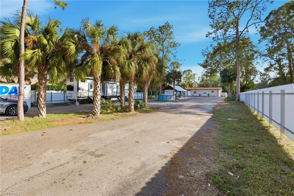 Spacious paved lot with a white privacy fence and established palm trees