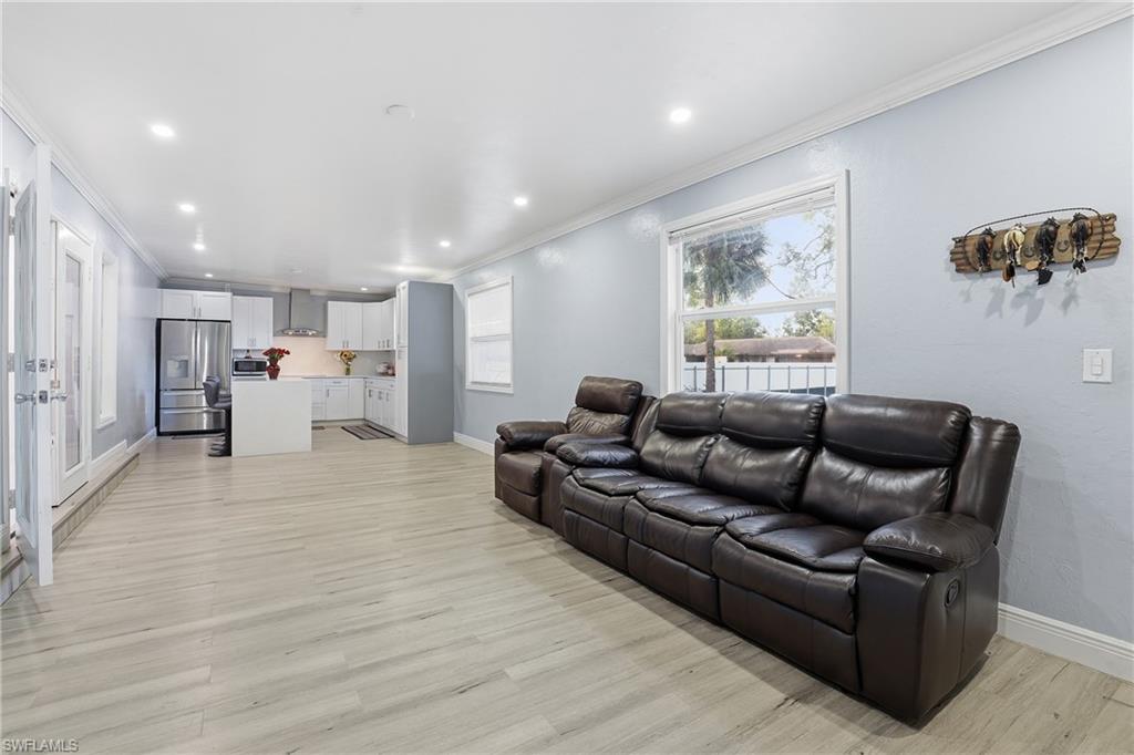 Open-concept living space featuring wood-finish flooring, recessed lighting, and crown molding