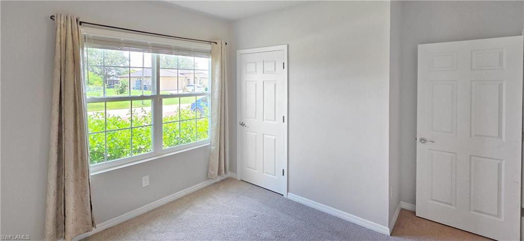 Carpeted room featuring a large window with white framing, light gray walls, and white trim