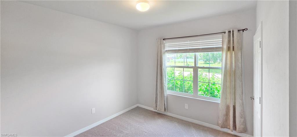 Bedroom featuring a large window with horizontal blinds and drapery, neutral-toned walls, and carpet flooring
