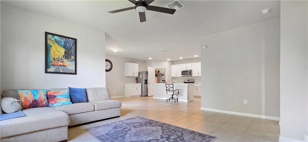 Open-concept living space featuring a ceiling fan, light-toned tile flooring, and neutral wall paint