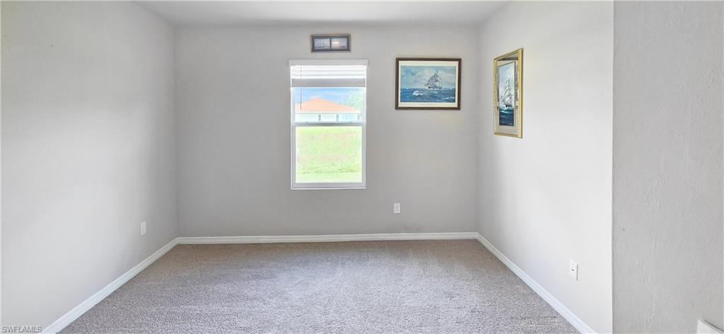Neutral-toned room featuring a single window with blinds and gray carpeting