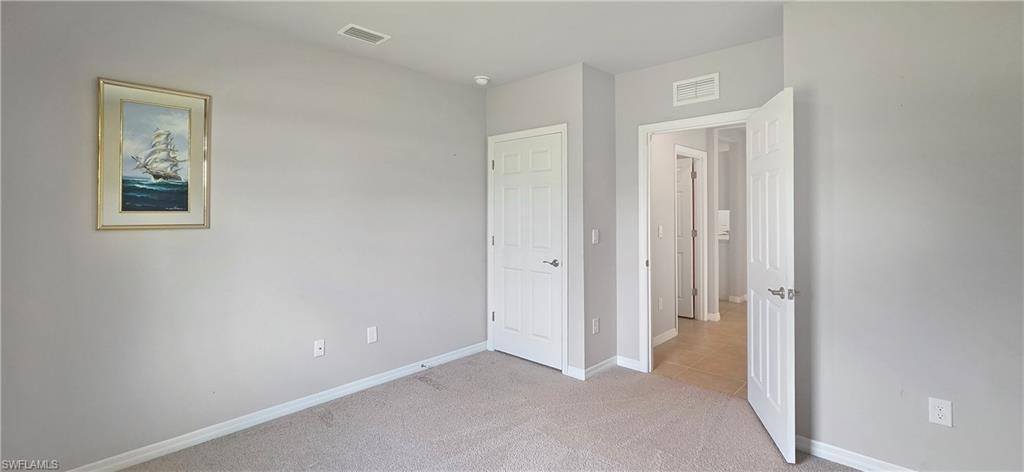 Carpeted room featuring light gray wall paint, white trim, and a paneled white door