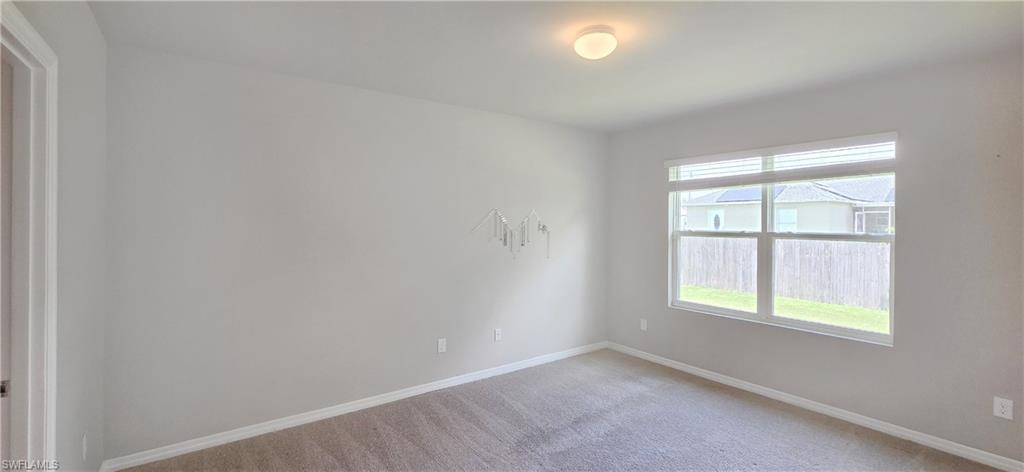 Light-filled room featuring neutral wall paint, a double window with blinds, and low-pile carpet flooring