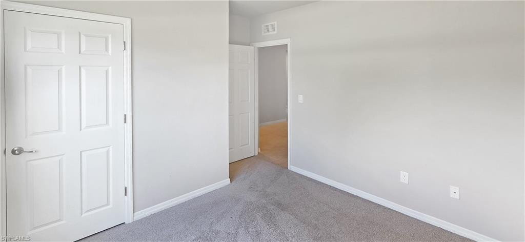 Gray carpeted room with white baseboards and neutral painted walls