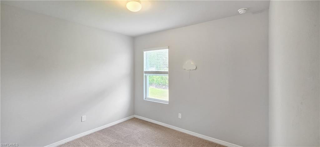 Neutral-toned room featuring a single window with blinds, carpeted flooring, and a flush-mount ceiling light