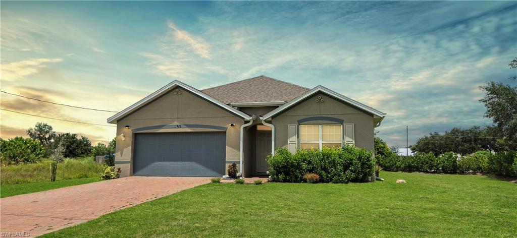 Stucco exterior with a shingle roof, attached two-car garage, and a paver driveway