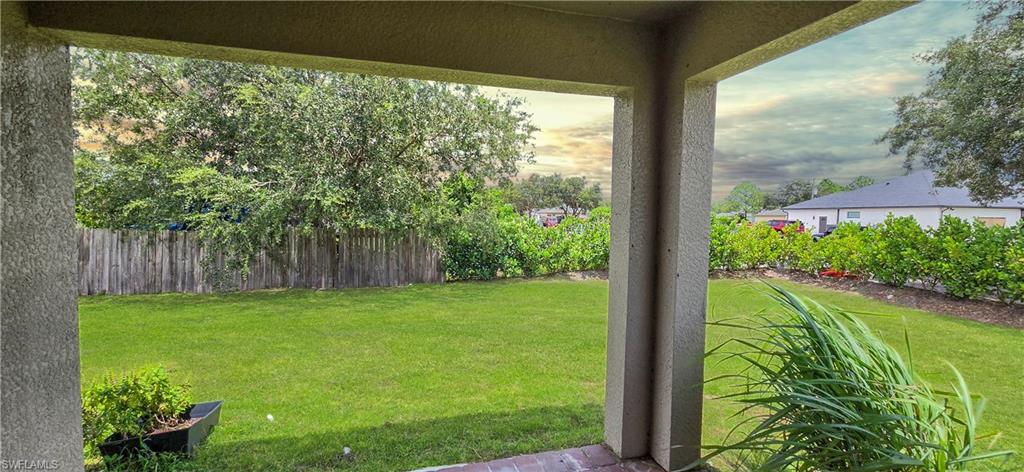 Expansive backyard featuring a manicured lawn, established privacy fence, mature trees, and structured landscaping