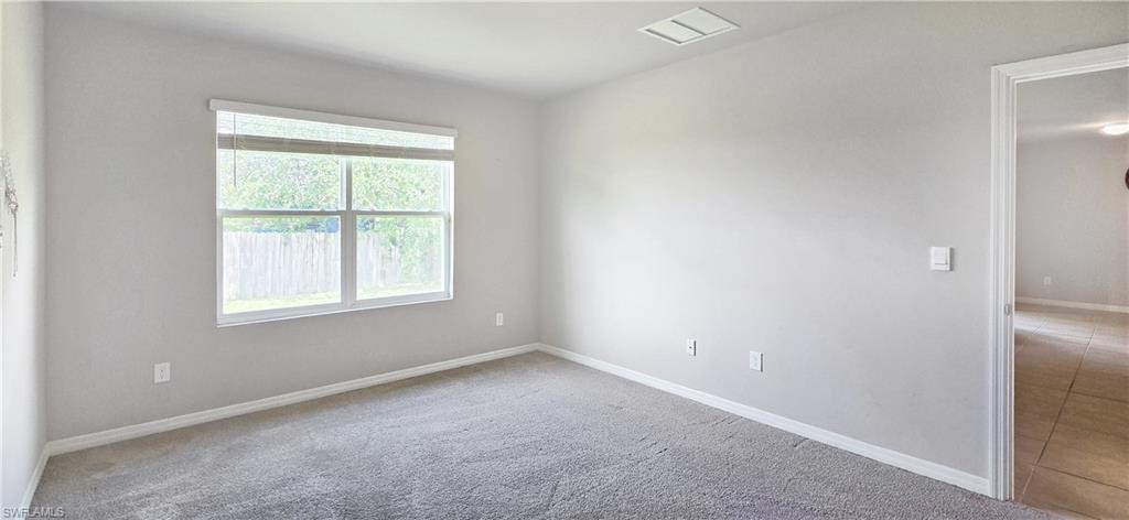 Spacious room featuring light gray carpeting, neutral wall paint, and a large window with horizontal blinds