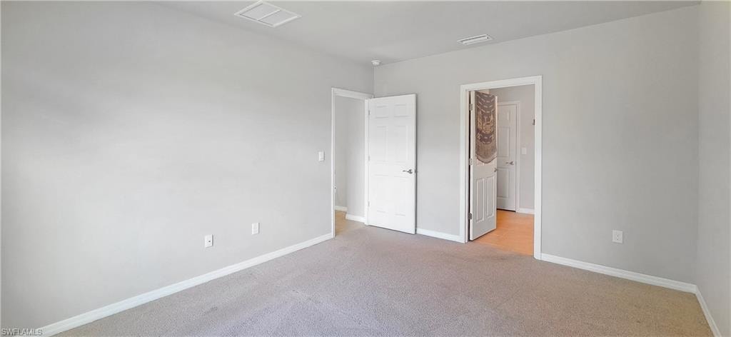 Carpeted interior room with light grey walls and white trim