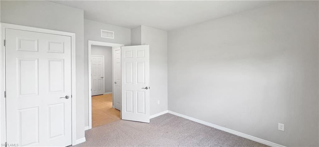 Light gray wall paint with white trim, gray carpet flooring, and white paneled doors