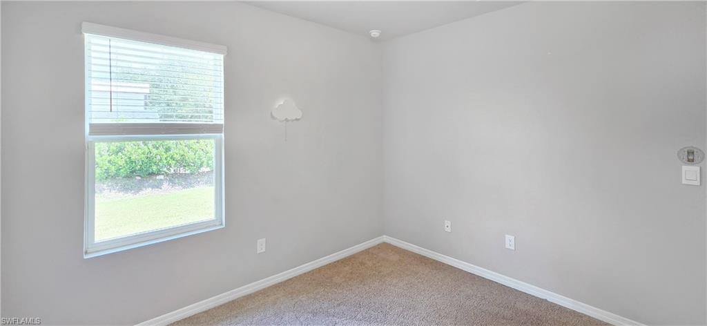 Window with blinds, wall-to-wall carpeting, light gray wall paint, white trim, and a wall-mounted light switch