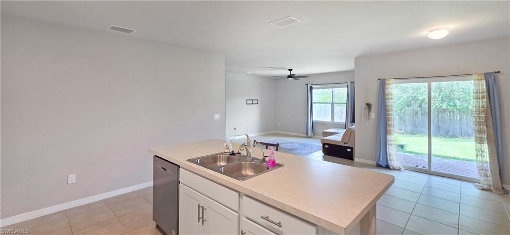 Kitchen island featuring a double basin stainless steel sink, light-toned countertop, and white cabinetry