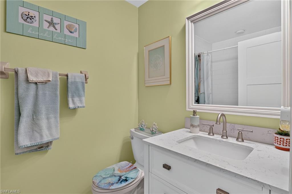 Bathroom featuring a white vanity with integrated sink, brushed nickel faucet, and a framed mirror