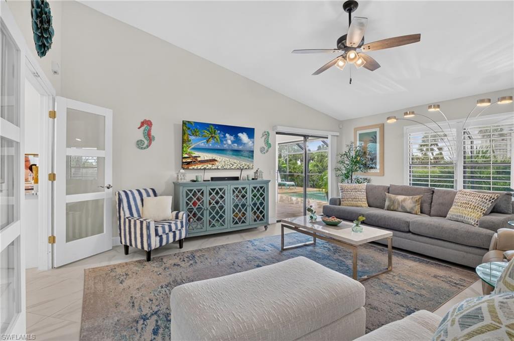 Spacious living area featuring a vaulted ceiling and a ceiling fan with integrated lighting