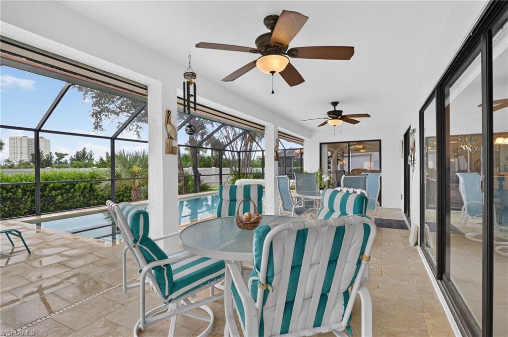 Expansive covered lanai with tile flooring, ceiling fans, and large sliding glass doors opening to the resort-style pool area